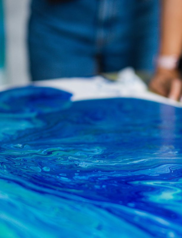 Person creating blue acrylic pour art on canvas. Art and creativity concept. Design for art class flyer, creative workshop, banner