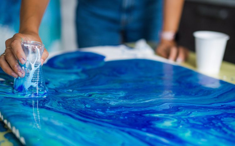 Person creating blue acrylic pour art on canvas. Art and creativity concept. Design for art class flyer, creative workshop, banner