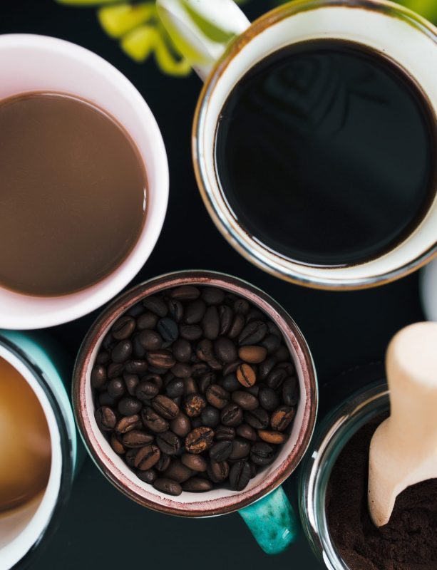 Multiple coffee cups, milk, beans and ground coffee in jar on black background. High quality photo